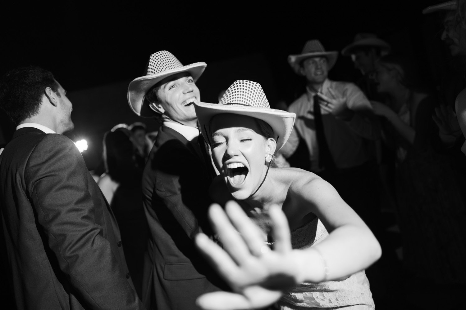 People wearing cowboy hats at a celebration, smiling and laughing in a black and white photo.
