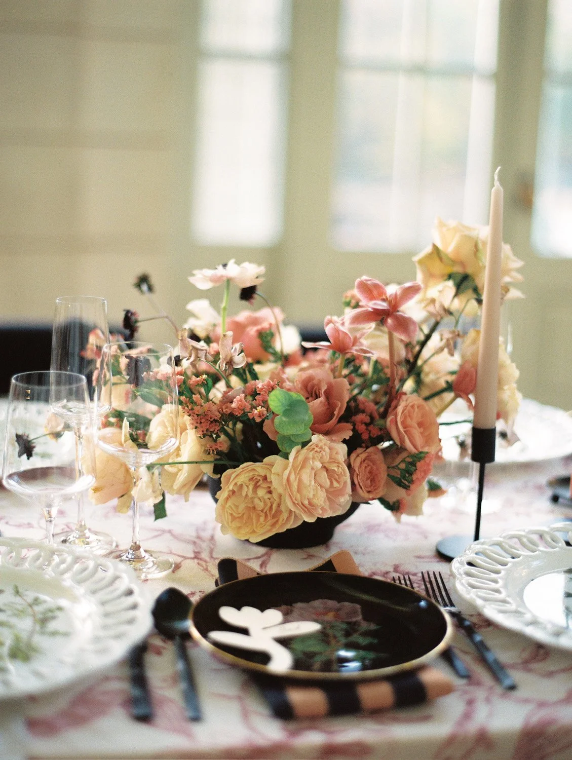 A table decorated with a floral centerpiece, candles, and place settings for a formal meal.