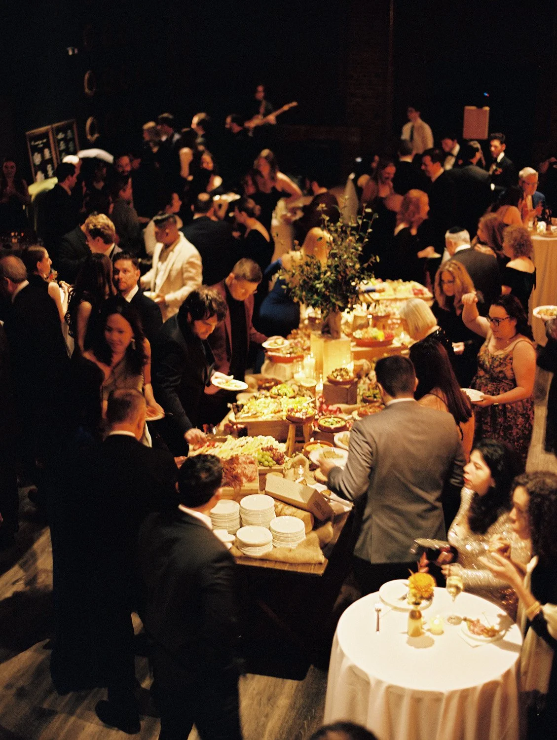 People gathered around a table with food at an elegant event or celebration.