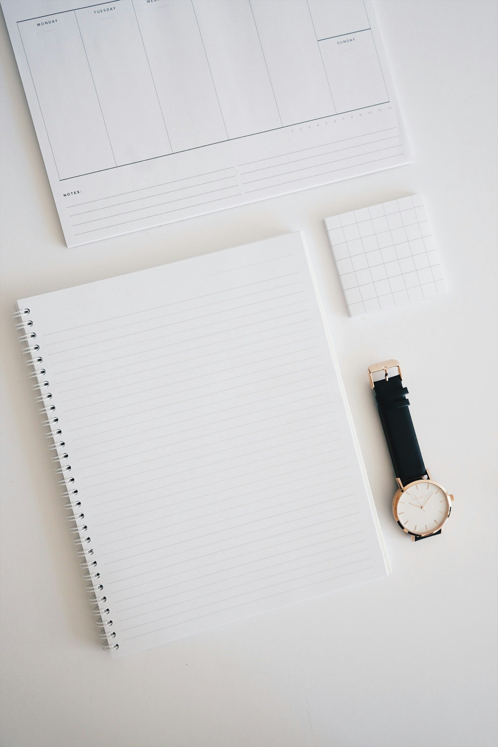 A structured grid arrangement of a minimalist watch and crisp gridded stationery, embodying rhythmic scheduling, meticulous organization, and methodological accounting rigor.