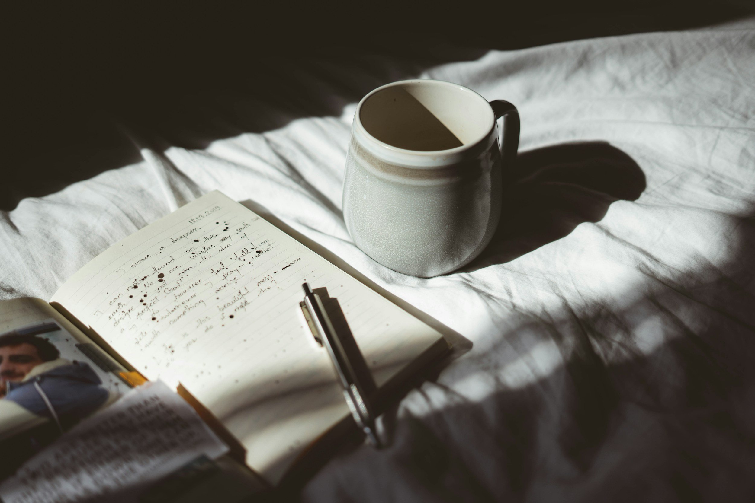 A quiet, editorial capture of a ceramic coffee mug sitting beside an open, handwritten journal, evoking a sense of deliberate focus, calm, and clarity amidst business operations.