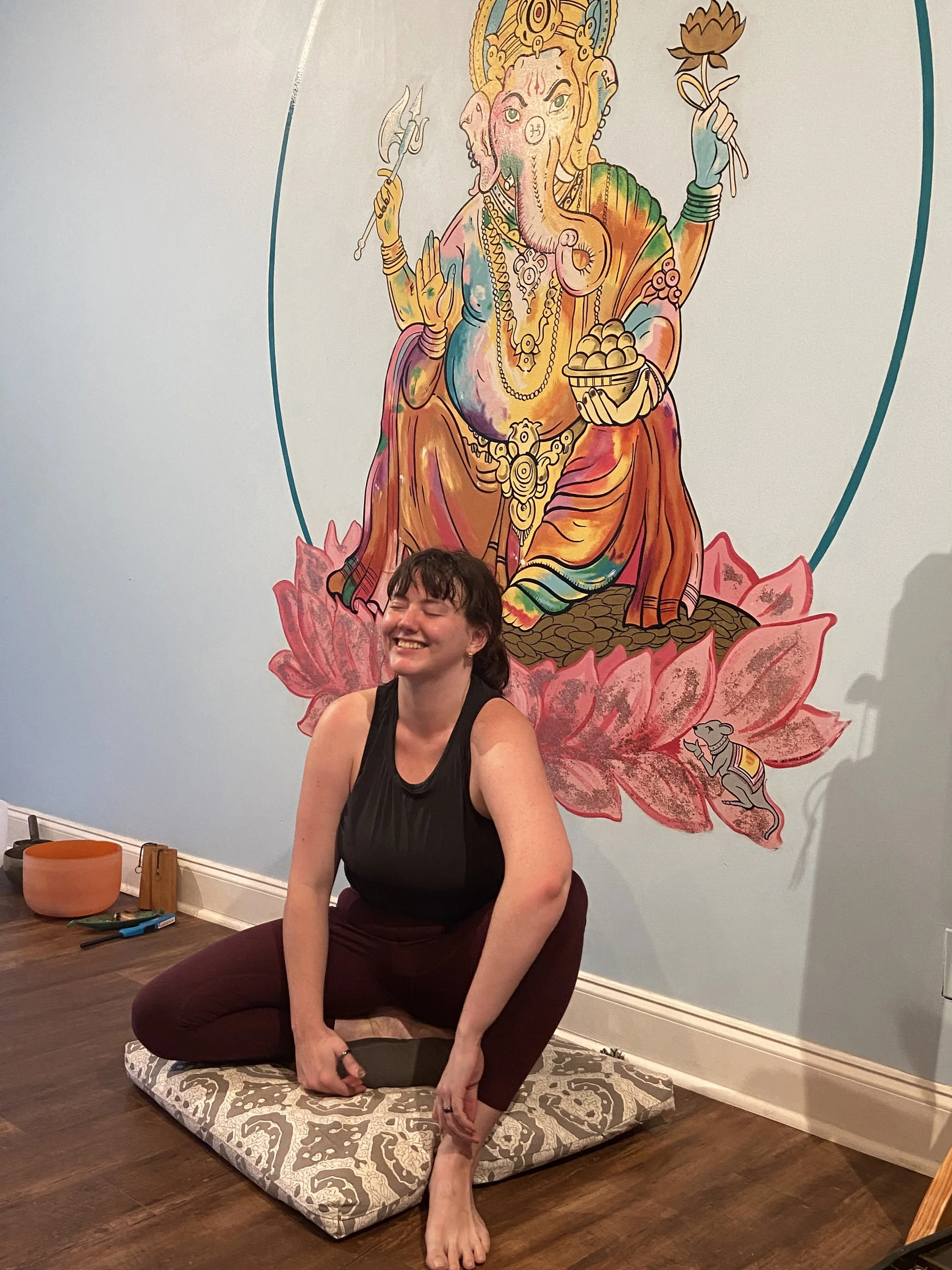 yoga instructor laughing in front of large image of Ganesha