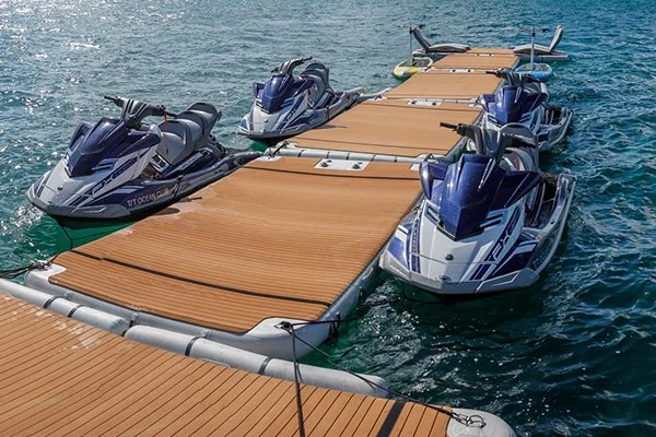 Four jet skis docked on a floating marina platform in open water.