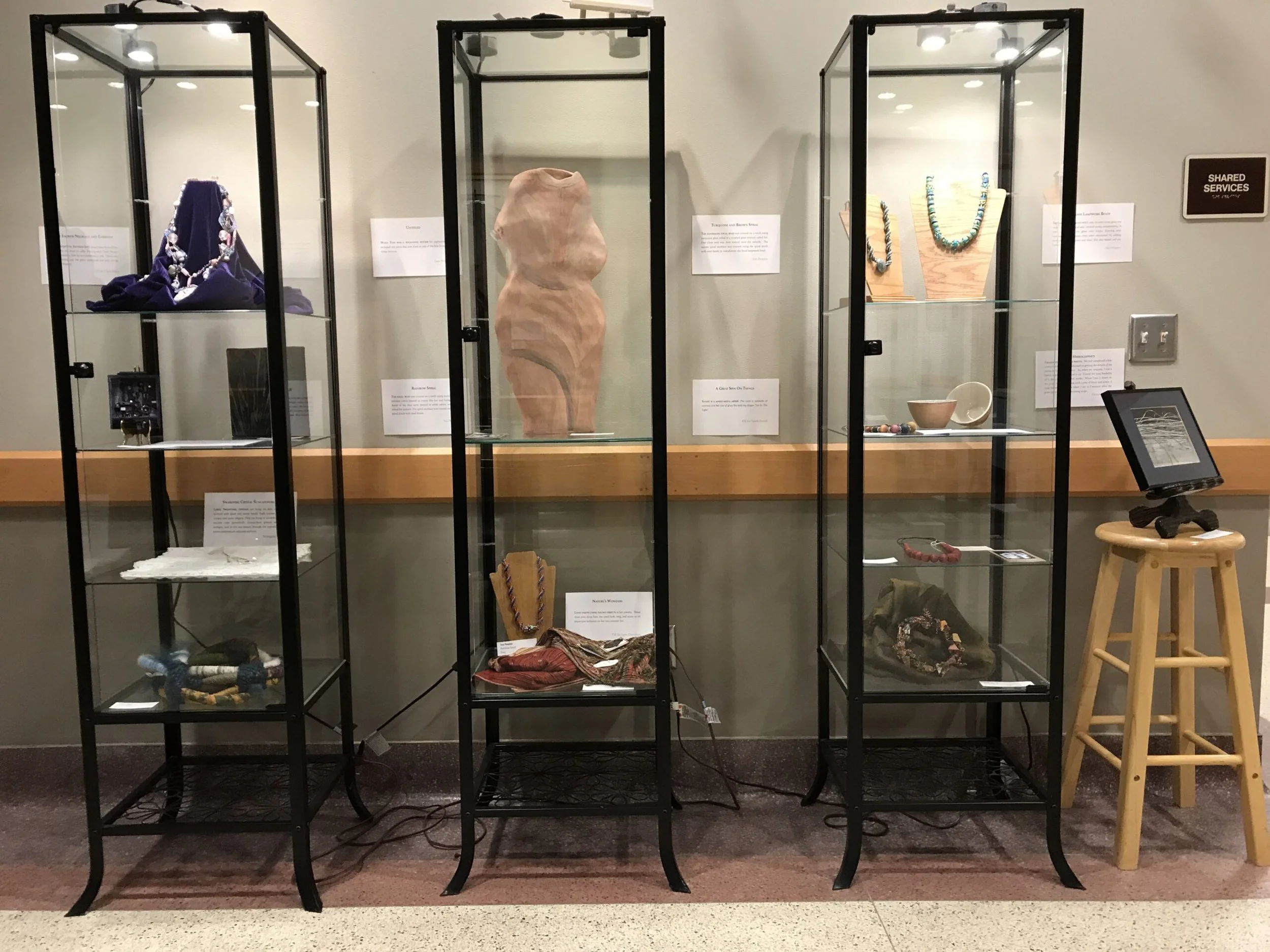 Display case with various artifacts including jewelry, pottery, and textiles inside for an exhibit.