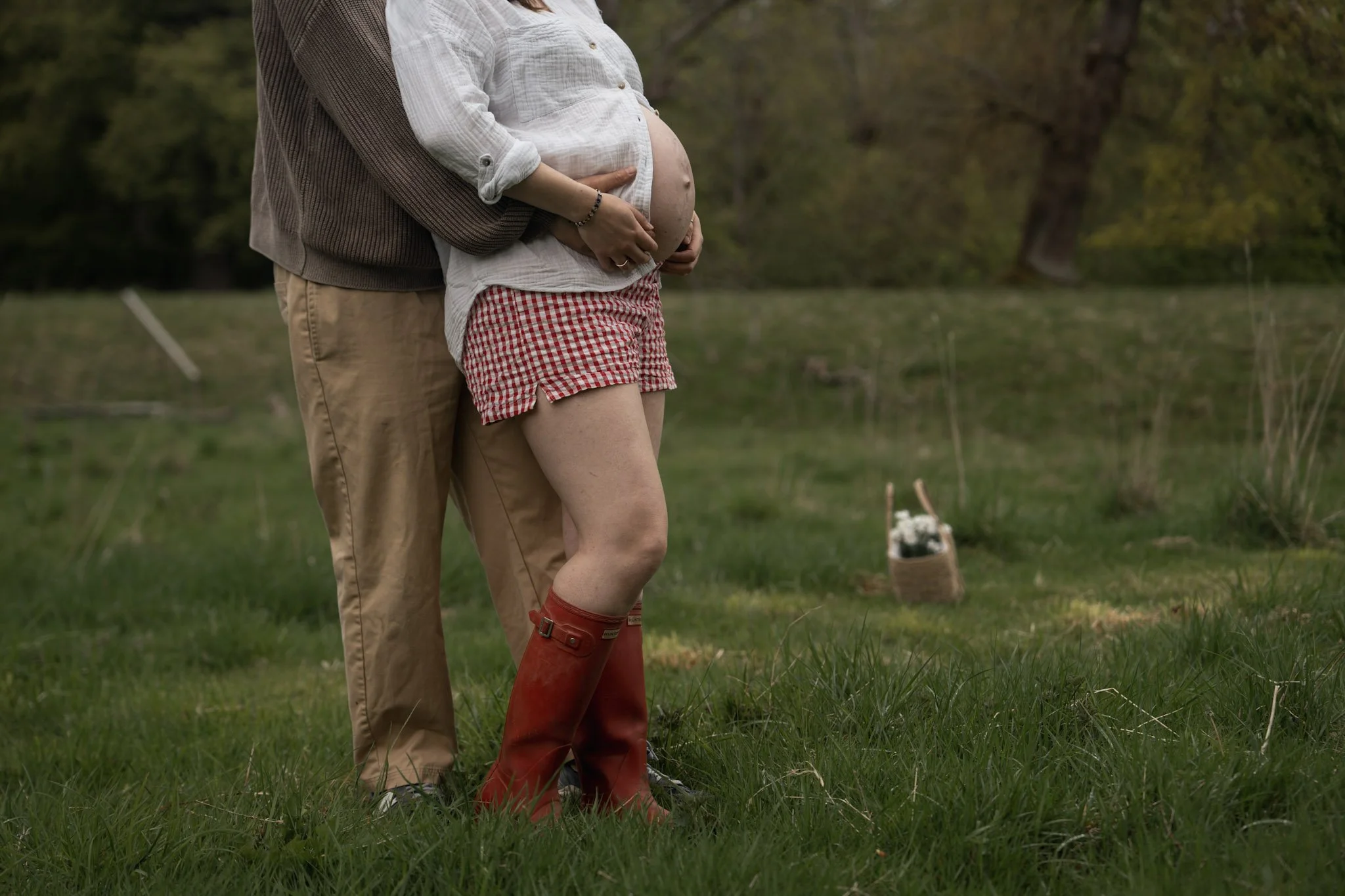 A low-angle detail shot of a couple in boots standing in a rugged green field in Scotland during an adventure maternity shoot.