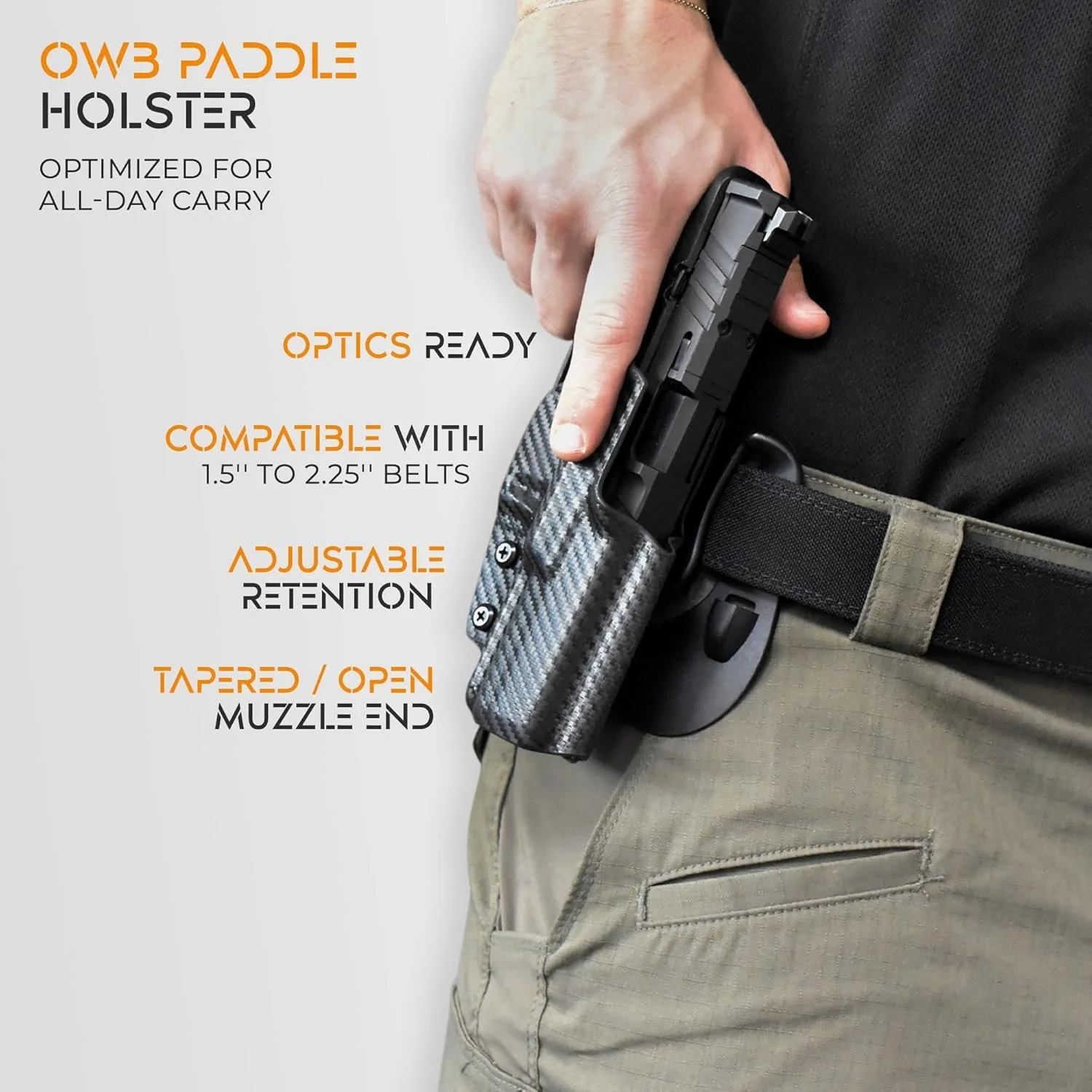 A person wearing khaki pants and a black shirt is carrying a black handgun in a carbon fiber patterned holster attached to a black adjustable belt. The image highlights the features of the OWB paddle holster, emphasizing that it is optimized for all-day carry, compatible with belts 1.5 to 2.25 inches wide, with optical readiness, adjustable retention, and a tapered open muzzle end.
