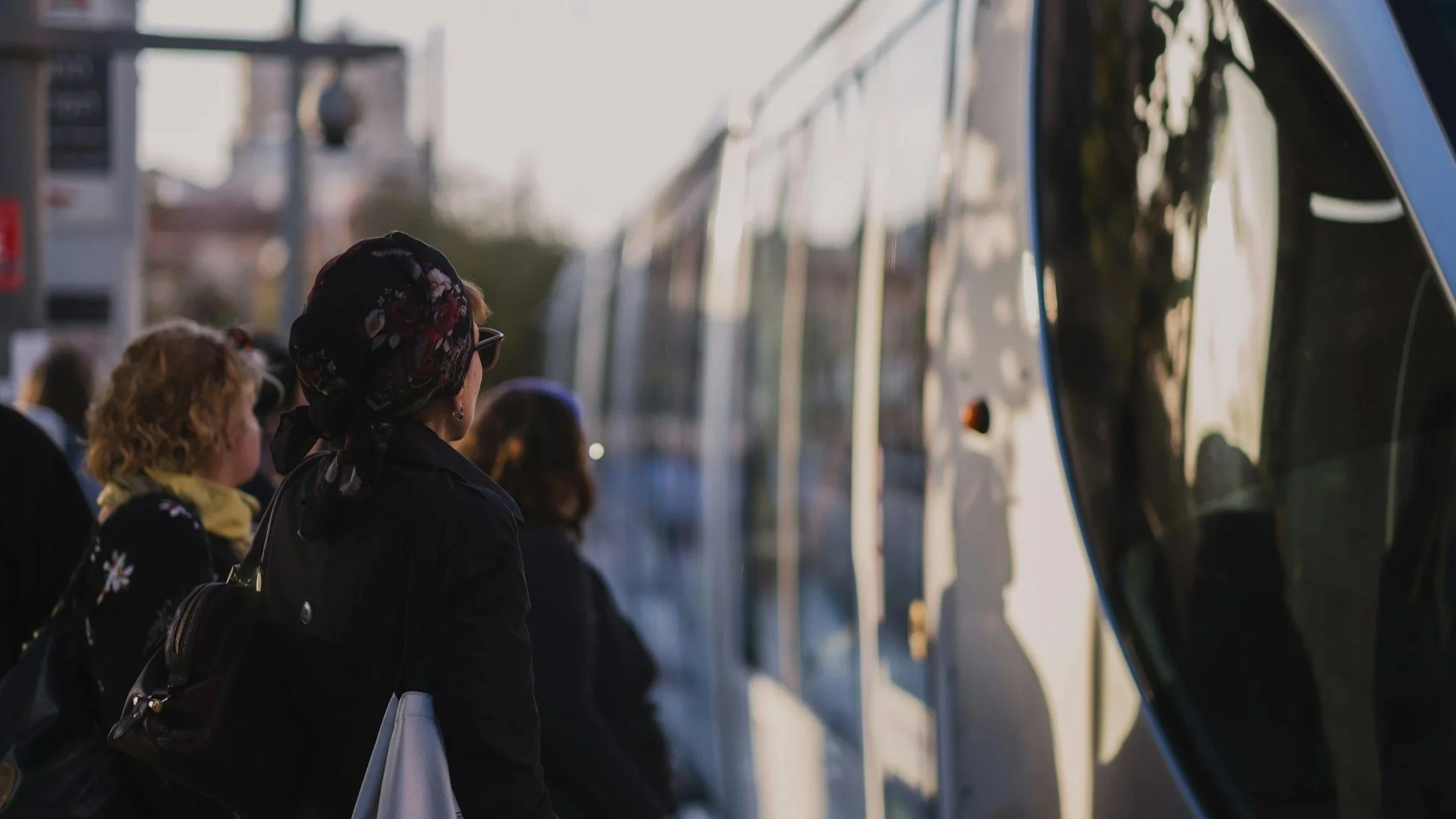 People waiting at a bus stop, looking at a bus.