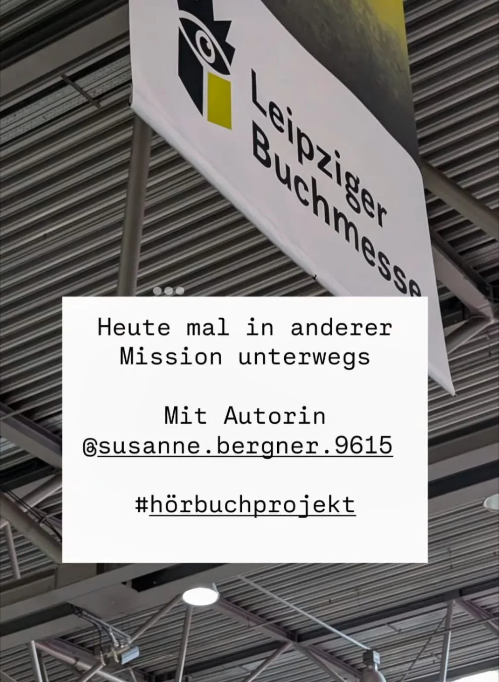 Ein schwarzes und weißes Schild mit der Aufschrift "Leipziger Buchmesse" hängt an einem Metalldach. Über dem Bild ist ein Textfeld mit der deutschen Beschreibung: "Heute mal in anderer Mission unterwegs Mit Autorin @susanne.bergner.9615 #hörbuchprojekt".