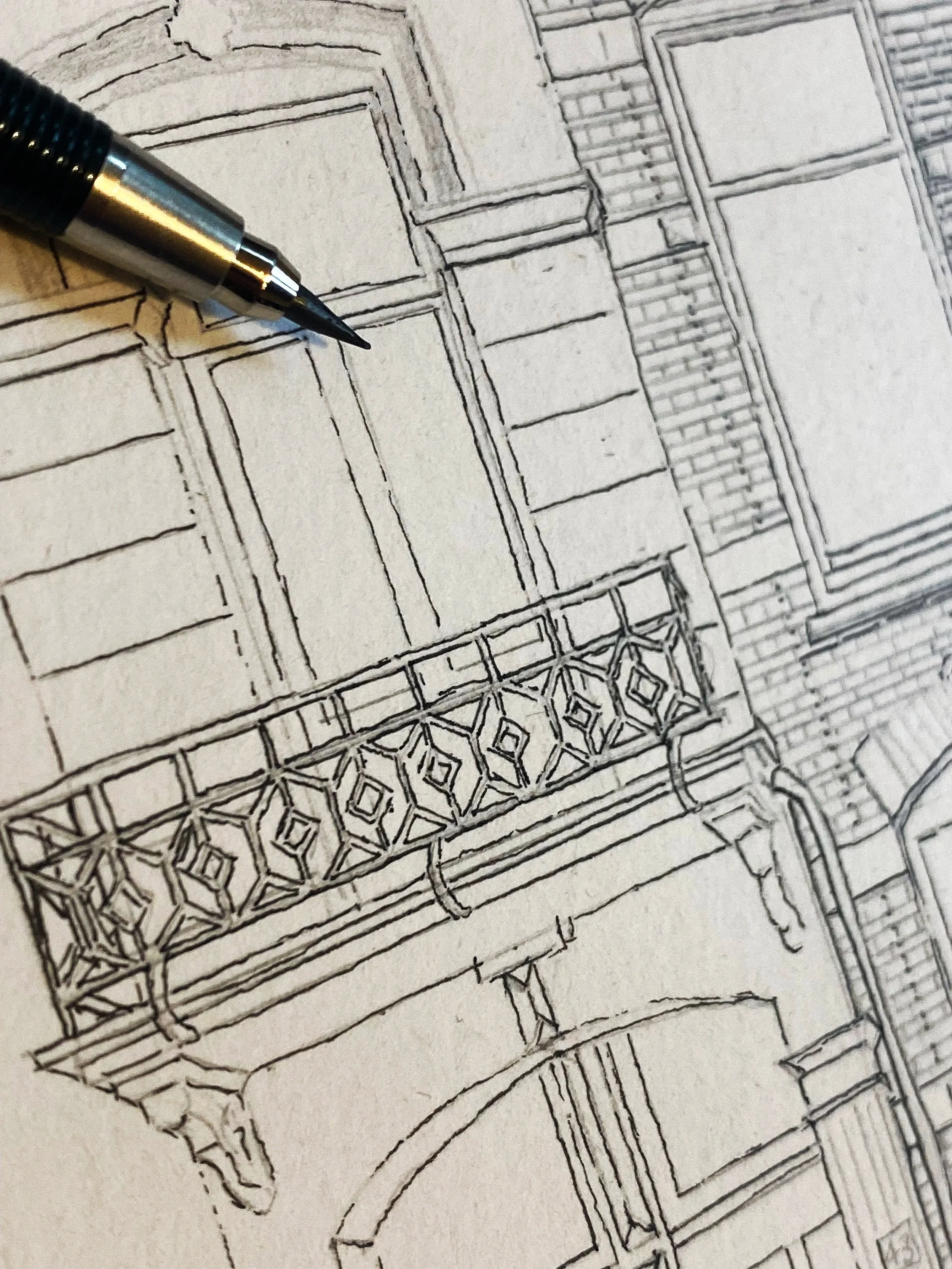A detailed architectural sketch of a building facade featuring windows, decorative balcony railing with intricate geometric patterns, and structural elements like columns and arches, created with precise black ink lines.