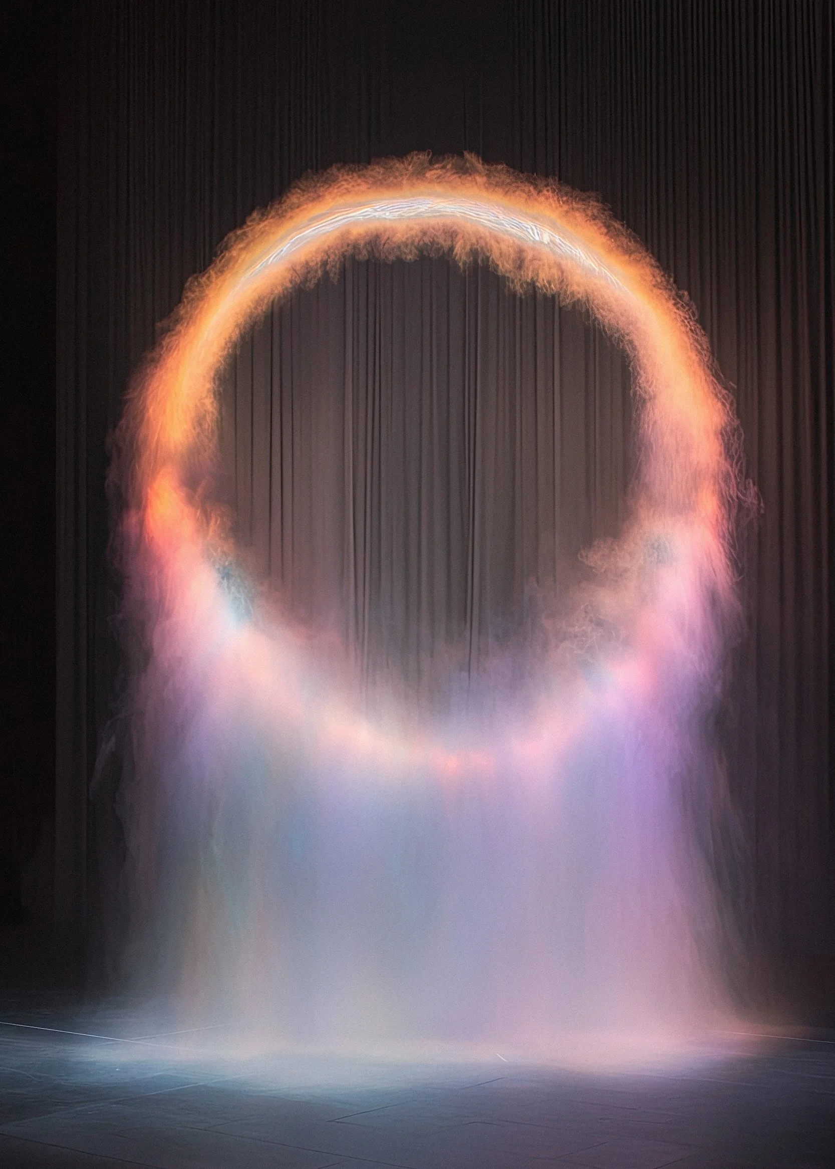 A large digital screen displays an abstract image of a glowing orange arc with wispy tendrils, against a dark background, creating a dramatic, fiery effect.