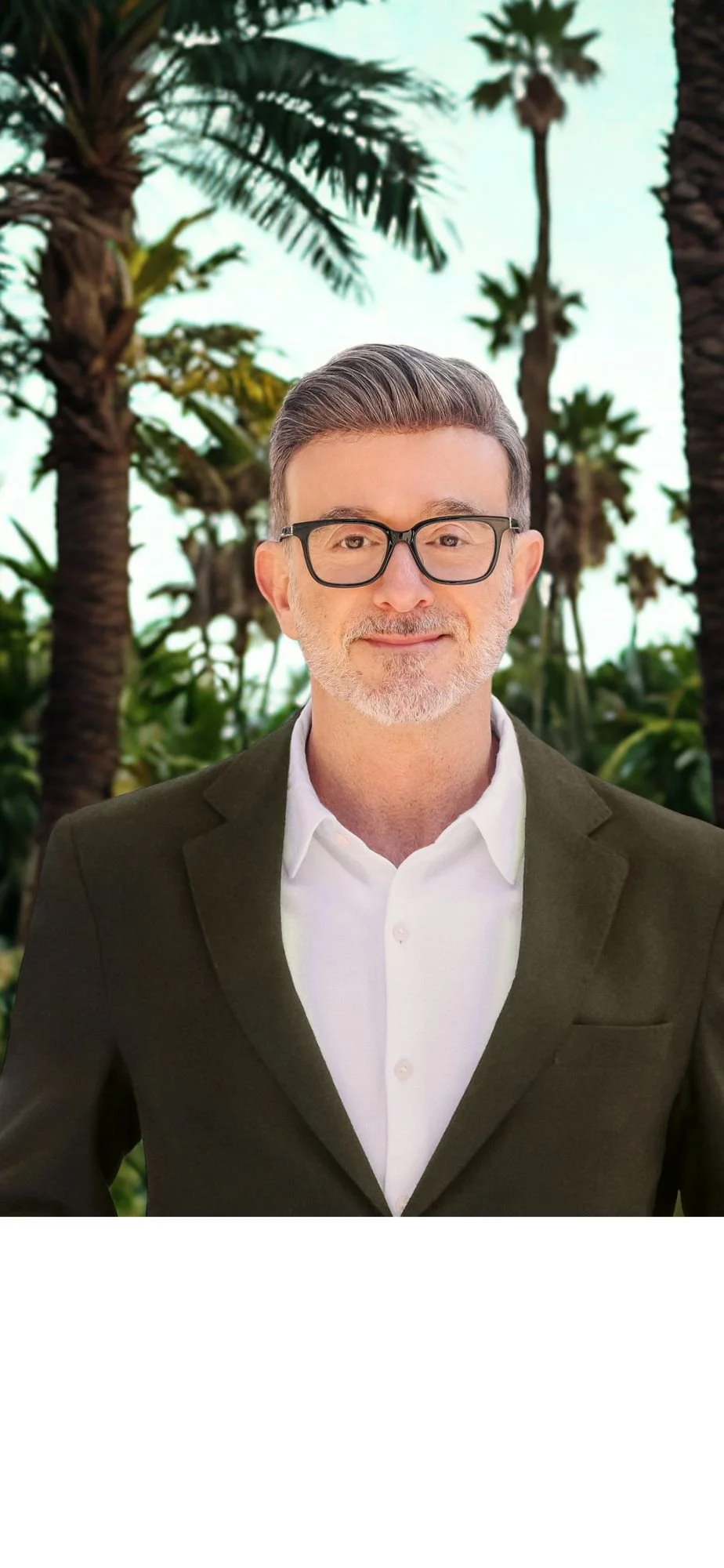 A middle-aged man with glasses, gray hair, and a beard, wearing a white shirt and a dark blazer, stands outdoors with palm trees in the background.