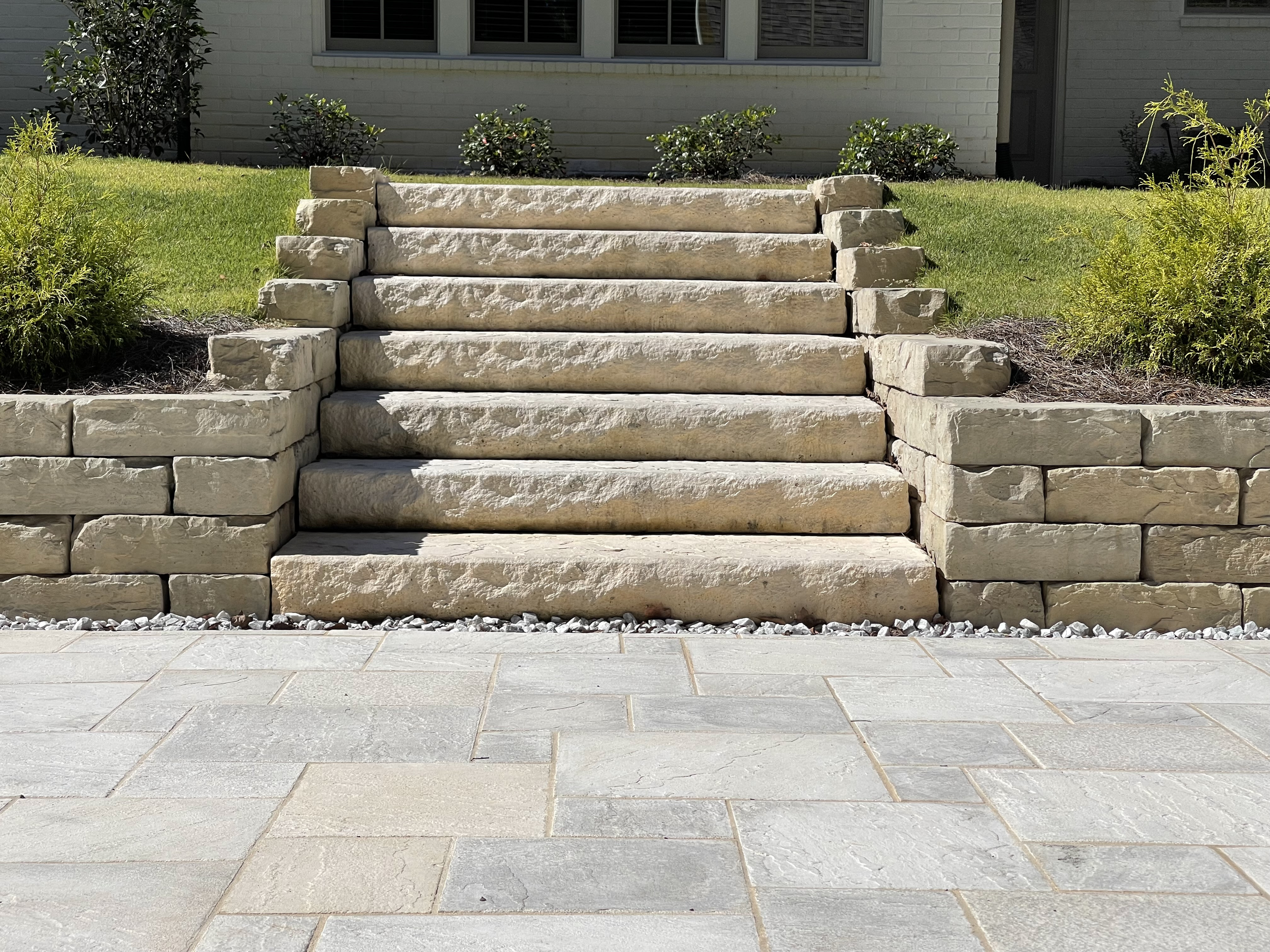 Steps to back travertine style patio.  Dimensional steps between natural look wall lead up to the house.