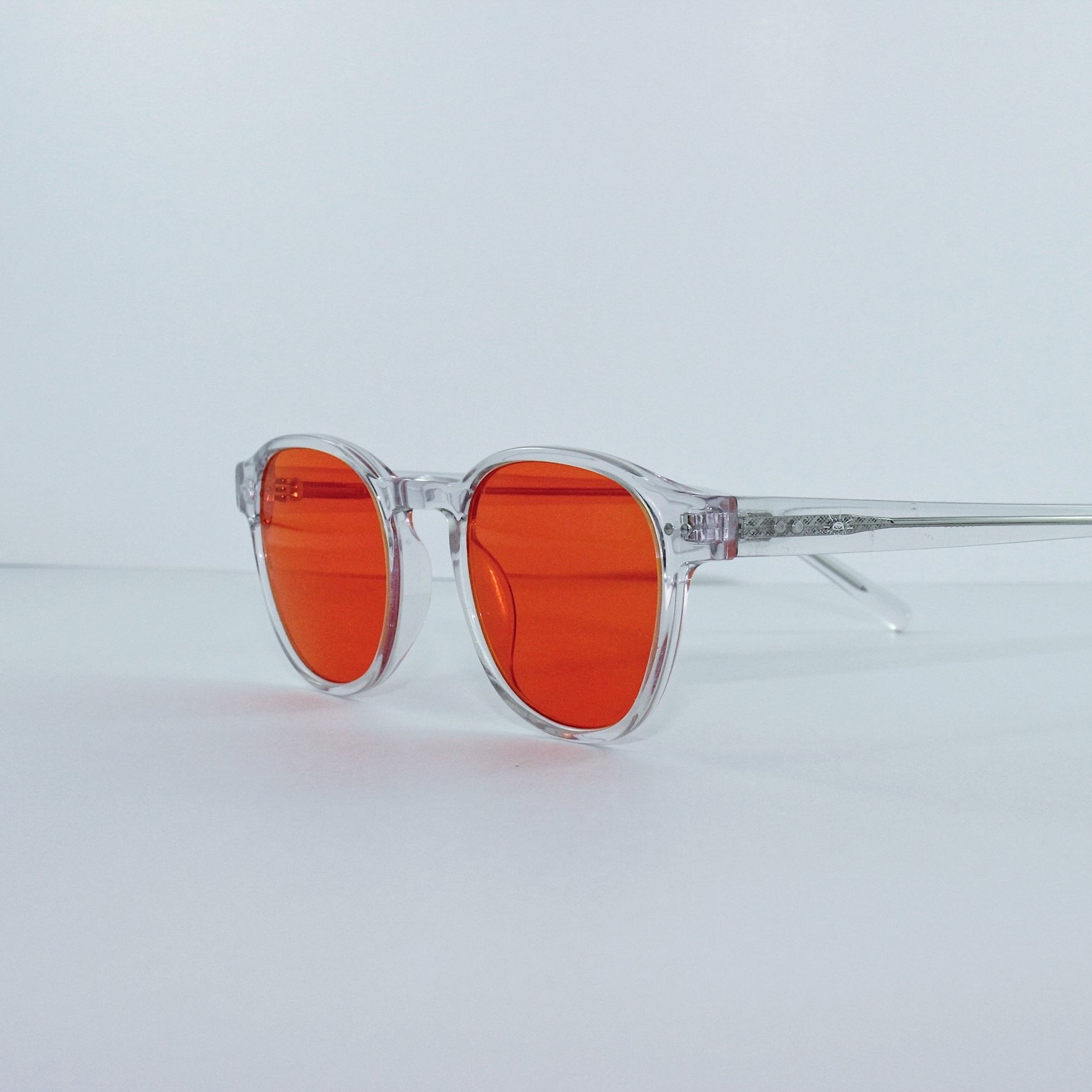 Clear-framed blue light glasses with orange lenses on a white background