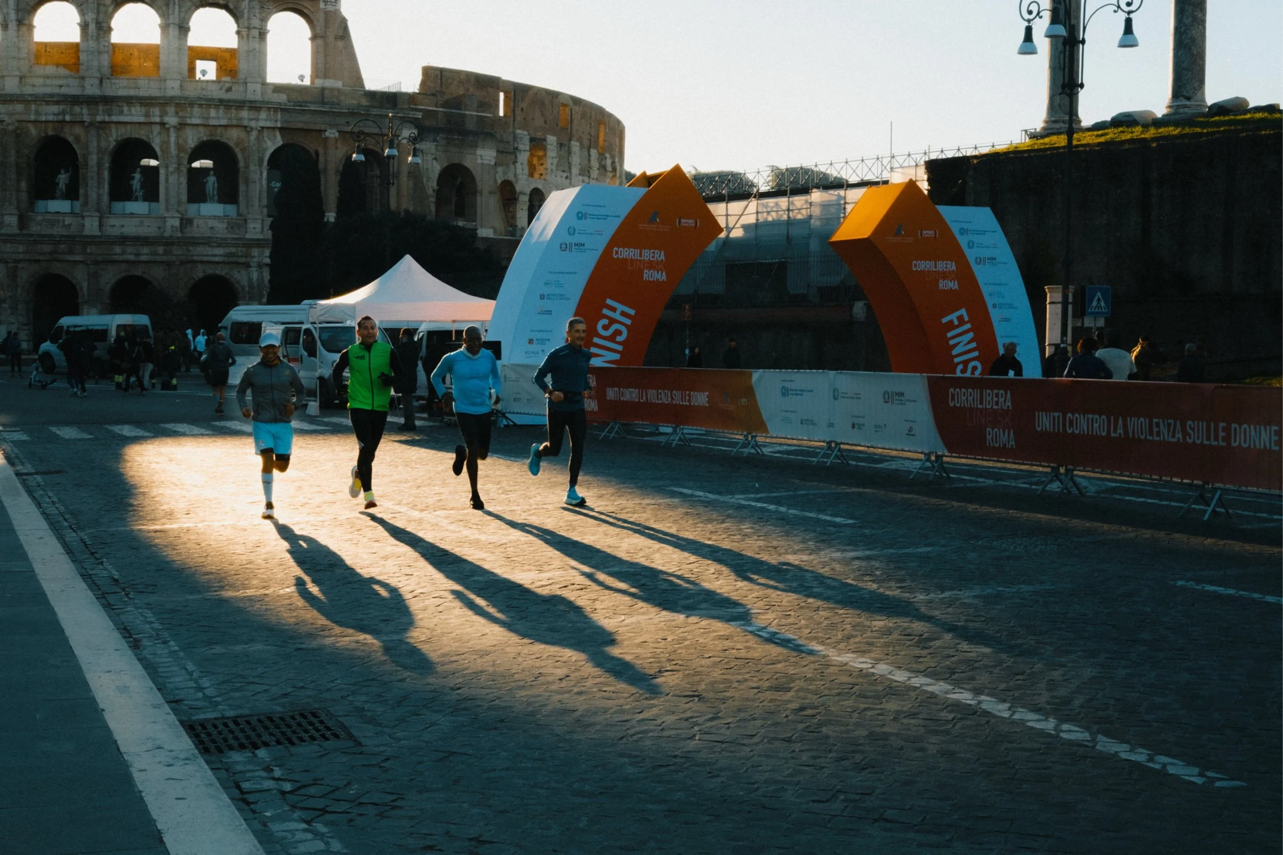People running in a marathon near the Roman Colosseum at sunrise or sunset.