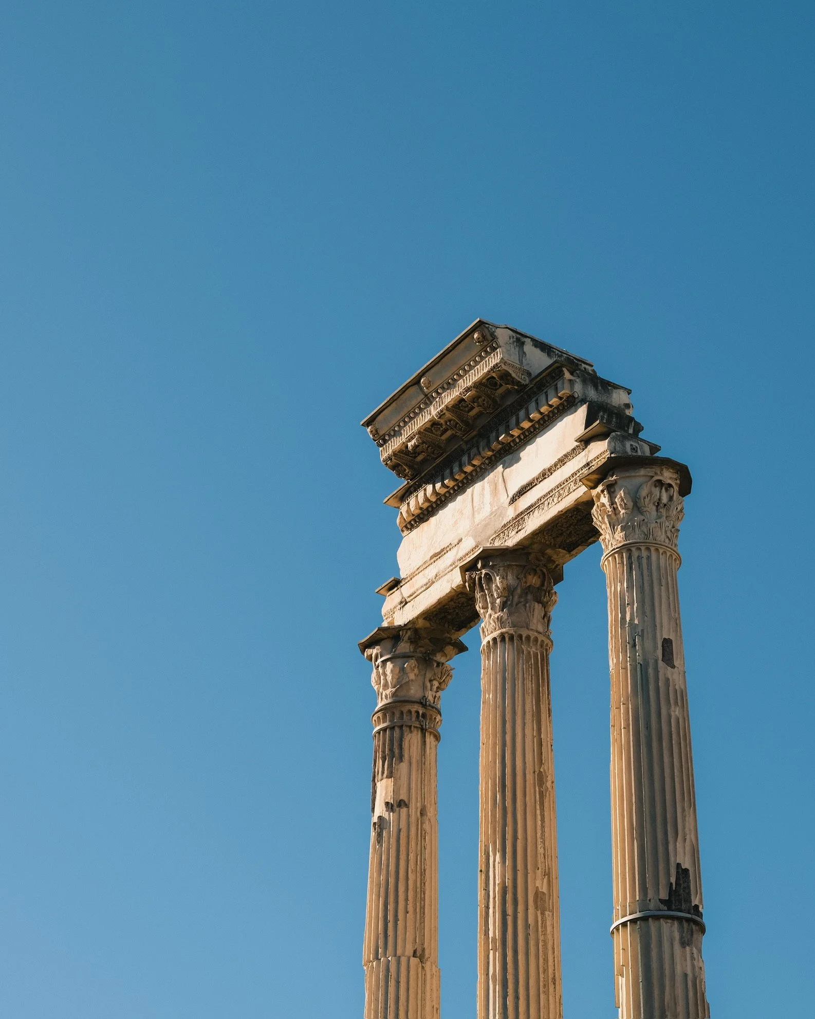 Ancient Greek or Roman architectural columns and capitals with a blue sky background.