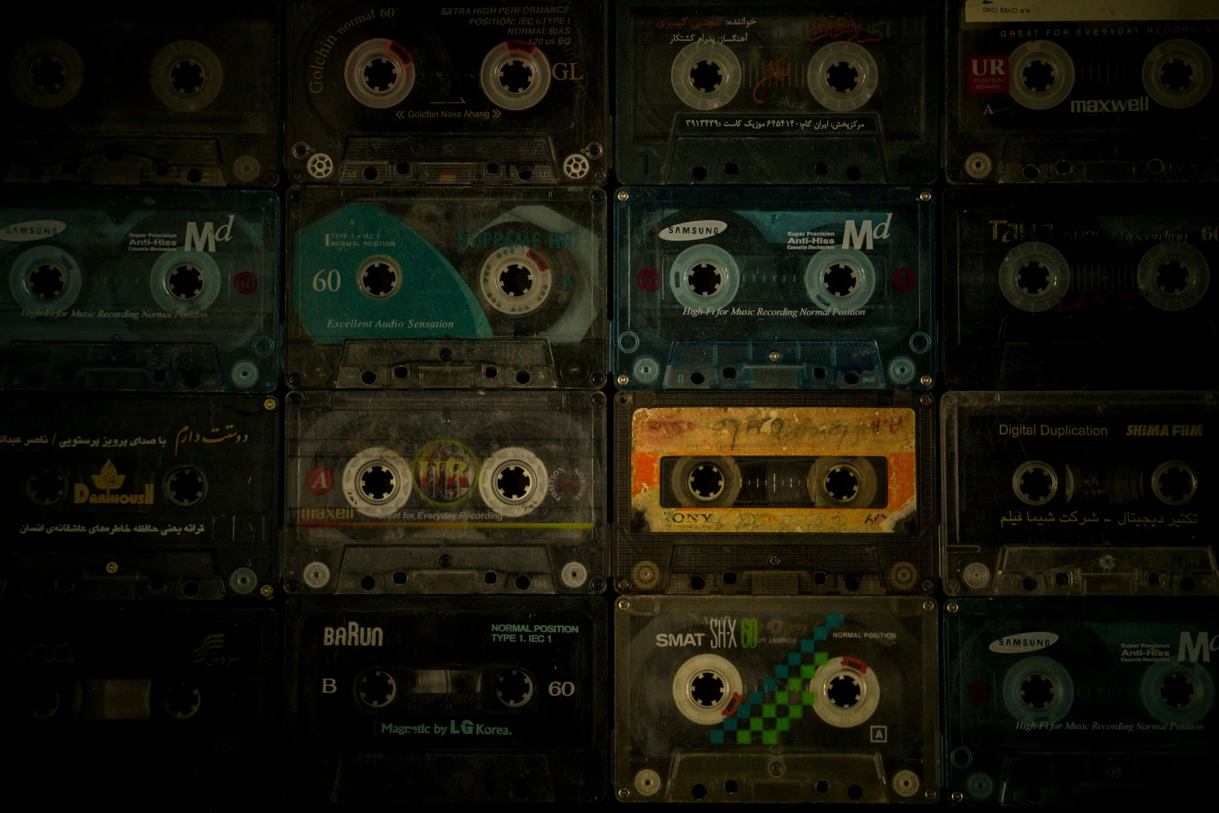 A collection of various audio cassette tapes with colorful labels arranged in a grid.