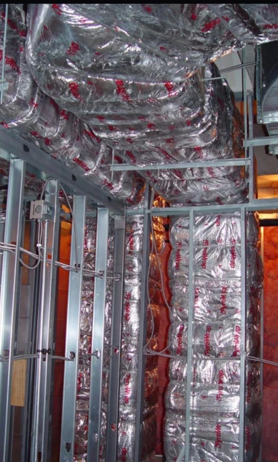 Construction site with metal framing, insulation, and wiring.