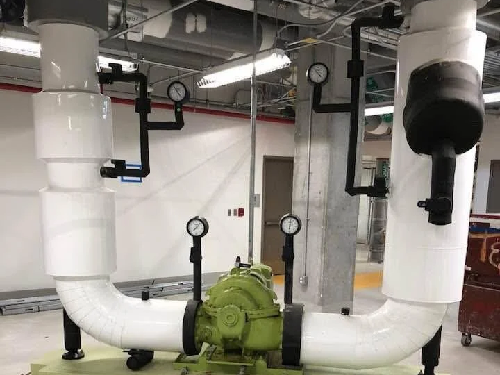 Industrial pipes and valves in a mechanical room.