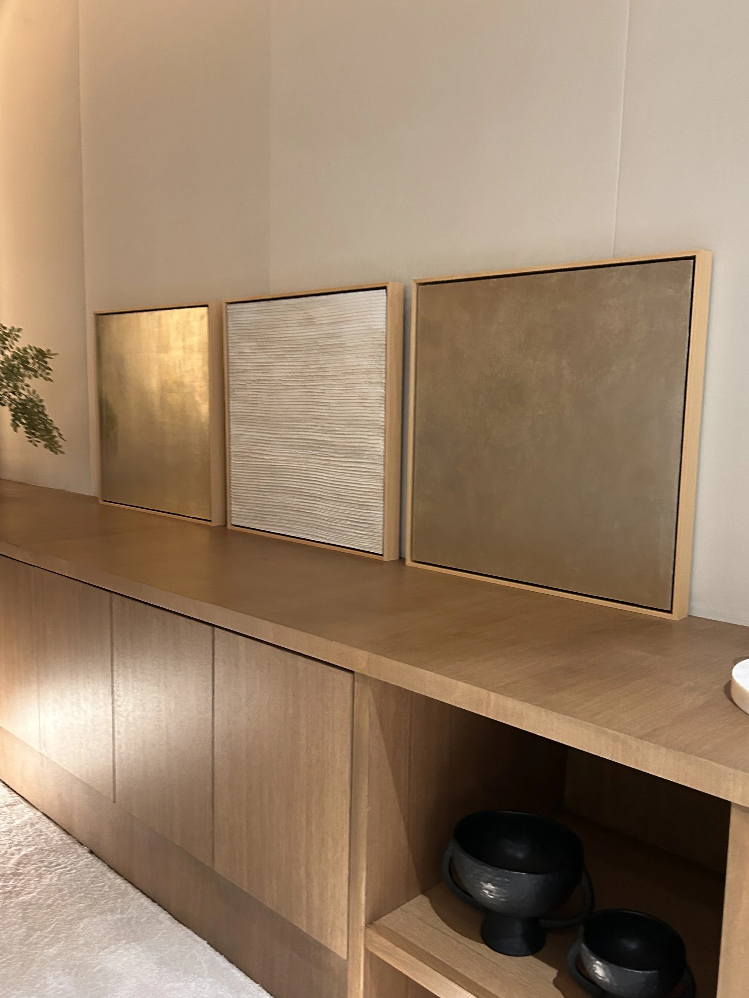 Wooden cabinet with three stick panels, a potted plant on the left, and three black bowls on the bottom right shelf.
