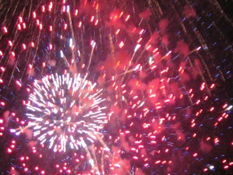 Colorful fireworks exploding in the night sky with red, white, and blue streaks.