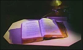 Open book illuminated by a purple light on a table