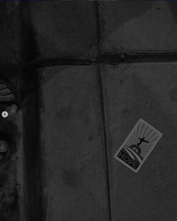 A sidewalk with a sticker of the Christ the Redeemer statue and the word "HOPE" on it, in black and white