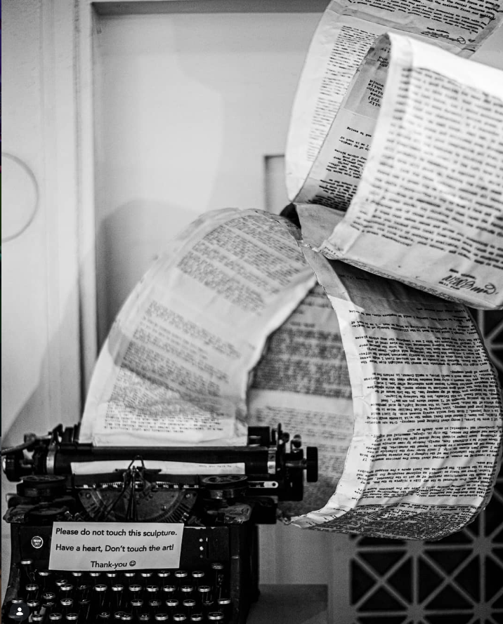 A vintage typewriter with a paper sculpture made of crumpled newspaper on top of it.