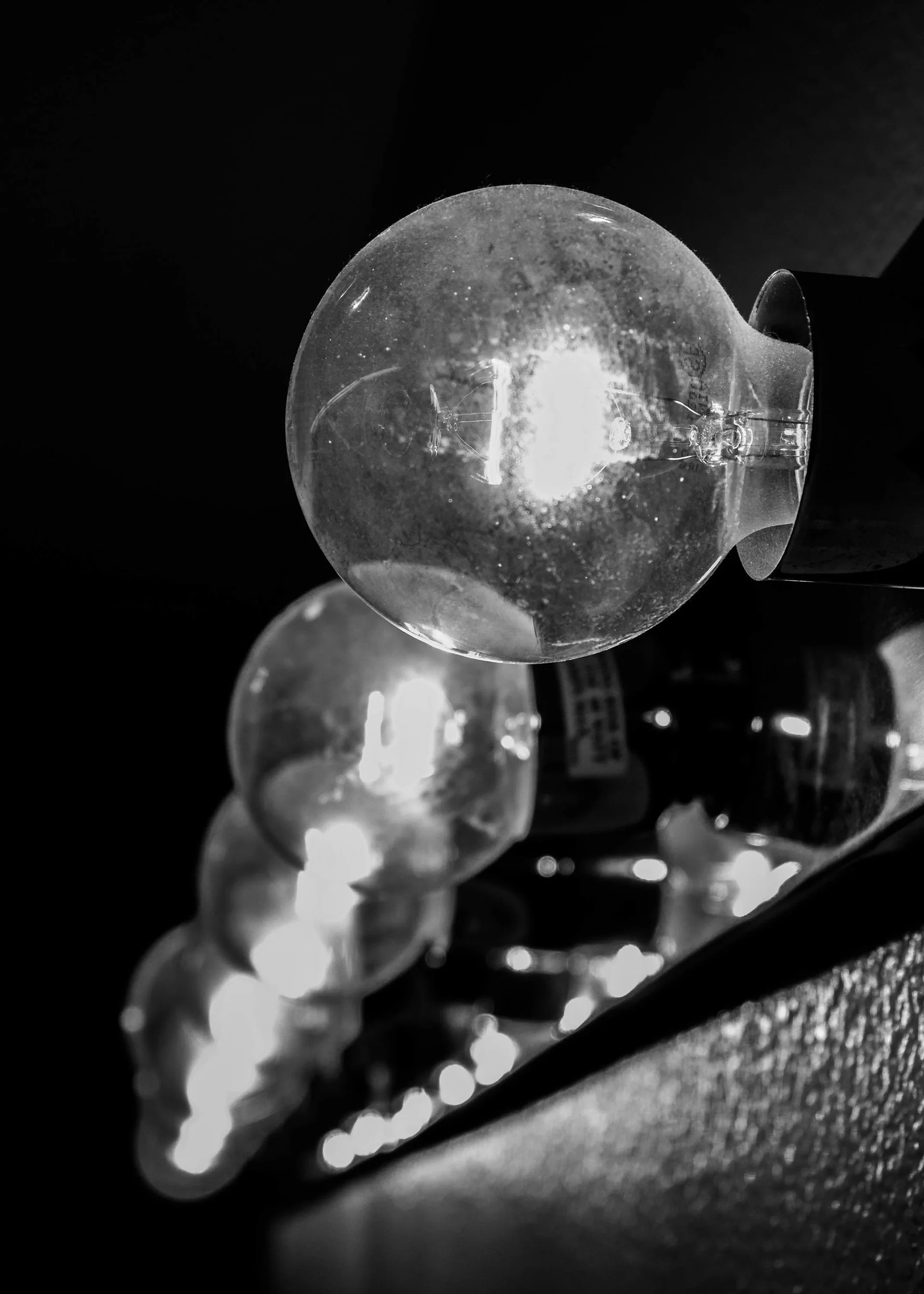 Close-up view of light bulbs on a string, illuminated in a dark setting, with a focus on one bulb