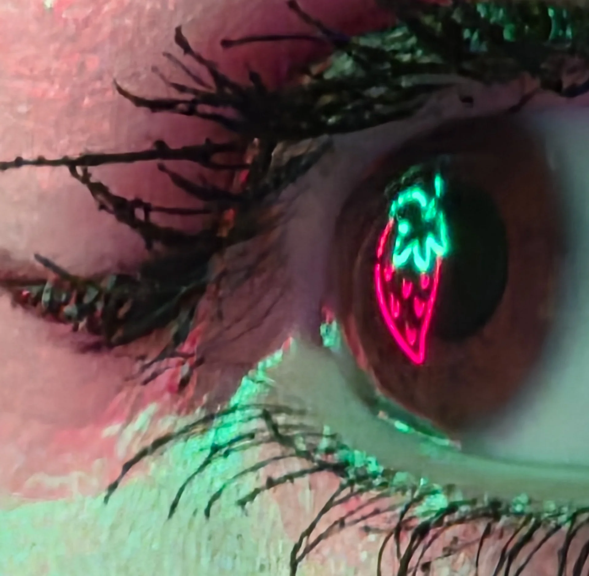 Close-up of a person's eye with a neon green and pink glow, with dark eyelashes and brightly lit skin