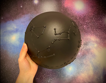 A hand holding a black 3D model of a constellation dome