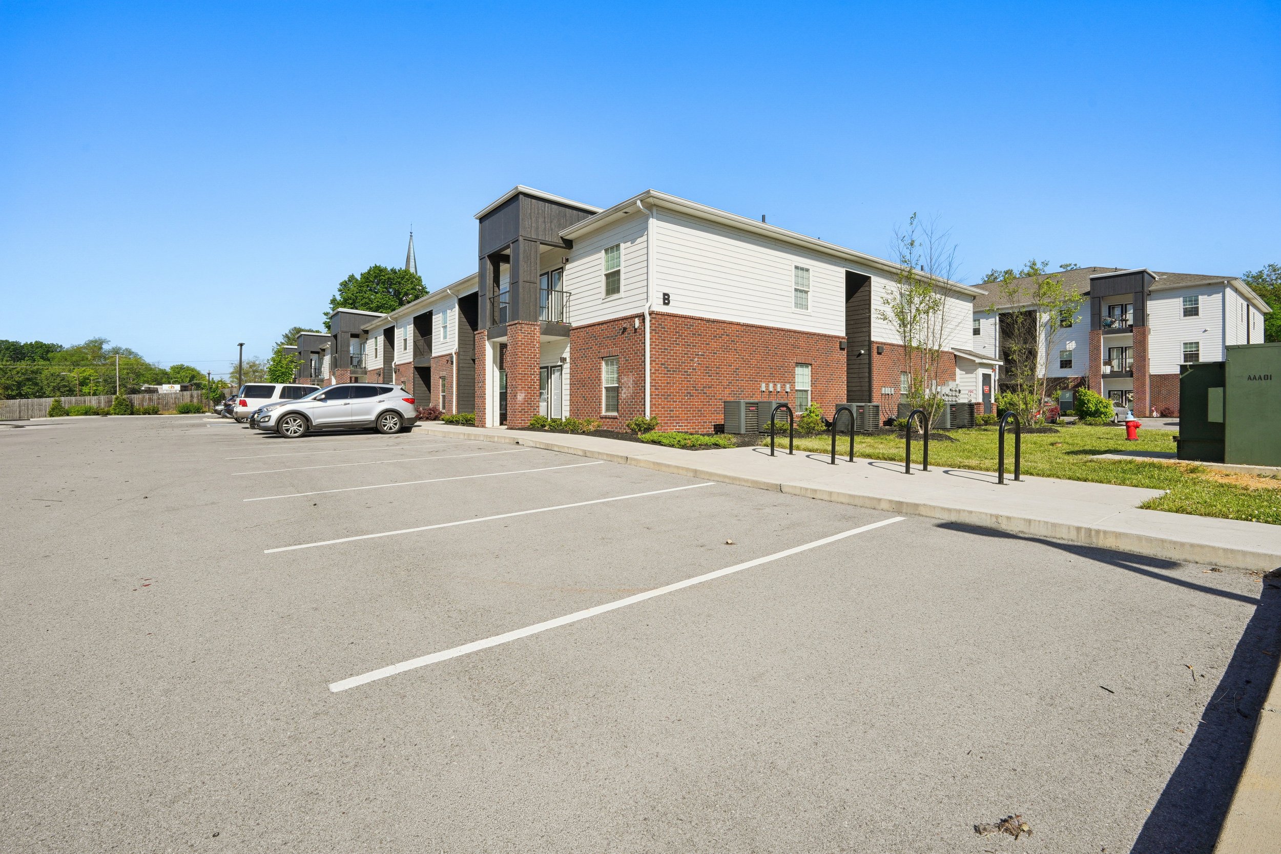 Empty parking lot in front of a residential apartment complex on a clear sunny day.