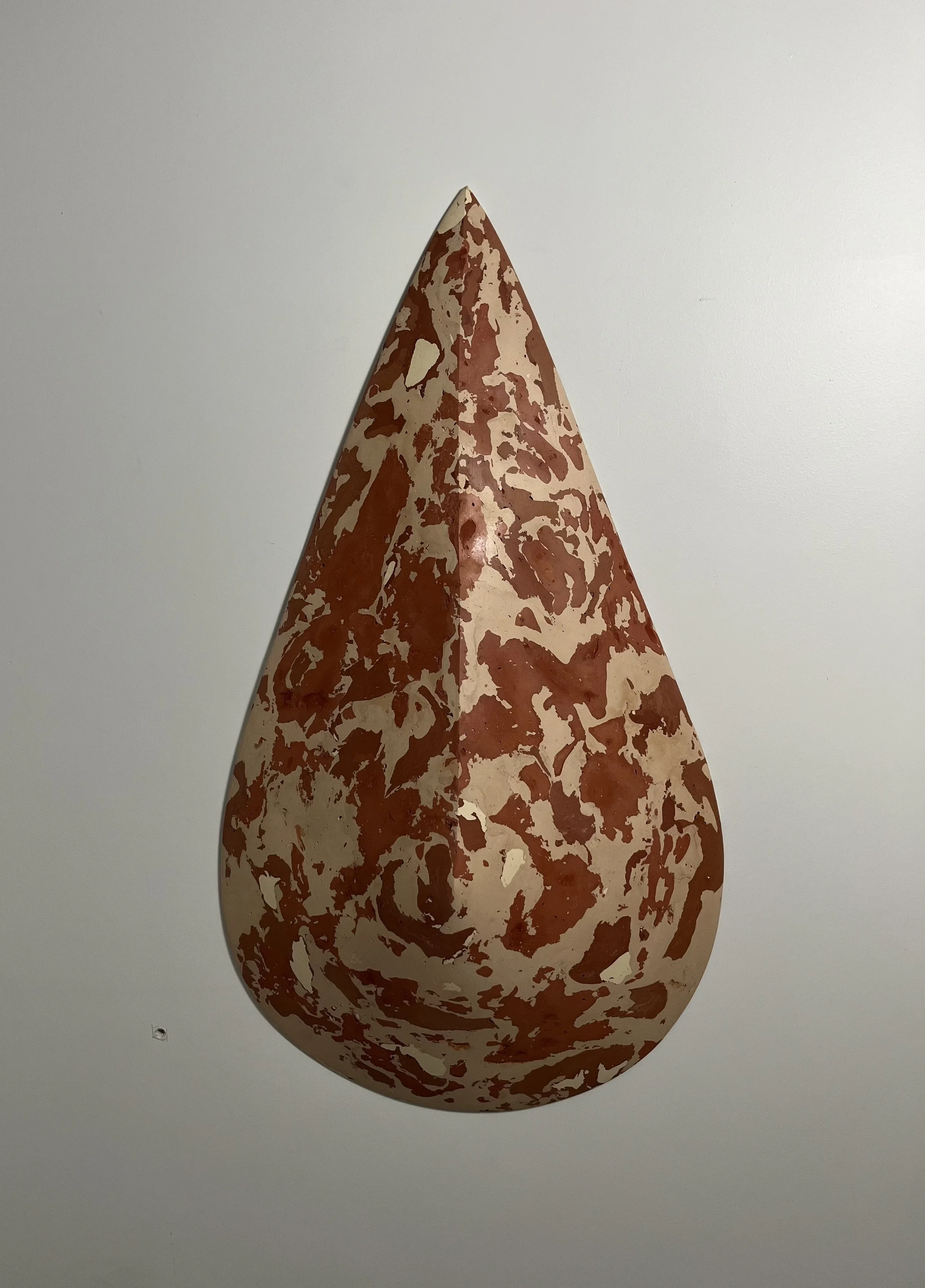 A large teardrop-shaped artwork with a cream background and reddish-brown abstract patterns, displayed on a white gallery wall.
