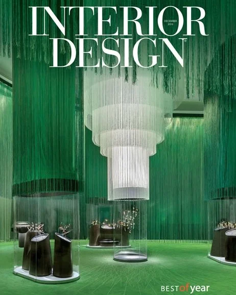 Cover of Interior Design magazine featuring a modern interior with a large white chandelier, green textured wall, and black display tables.