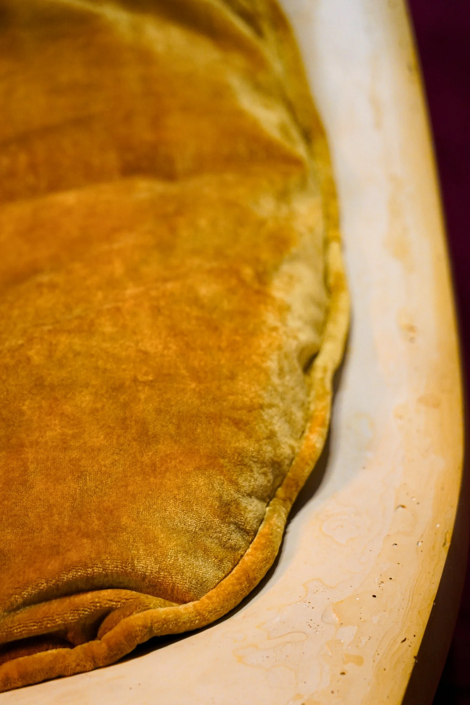 Close-up of a golden-brown crepe folded on a white plate with a marble pattern.