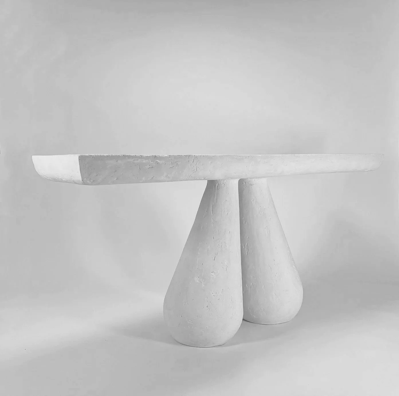 Black and white photo of a modern platform with three pedestal bases supporting a flat, circular top.