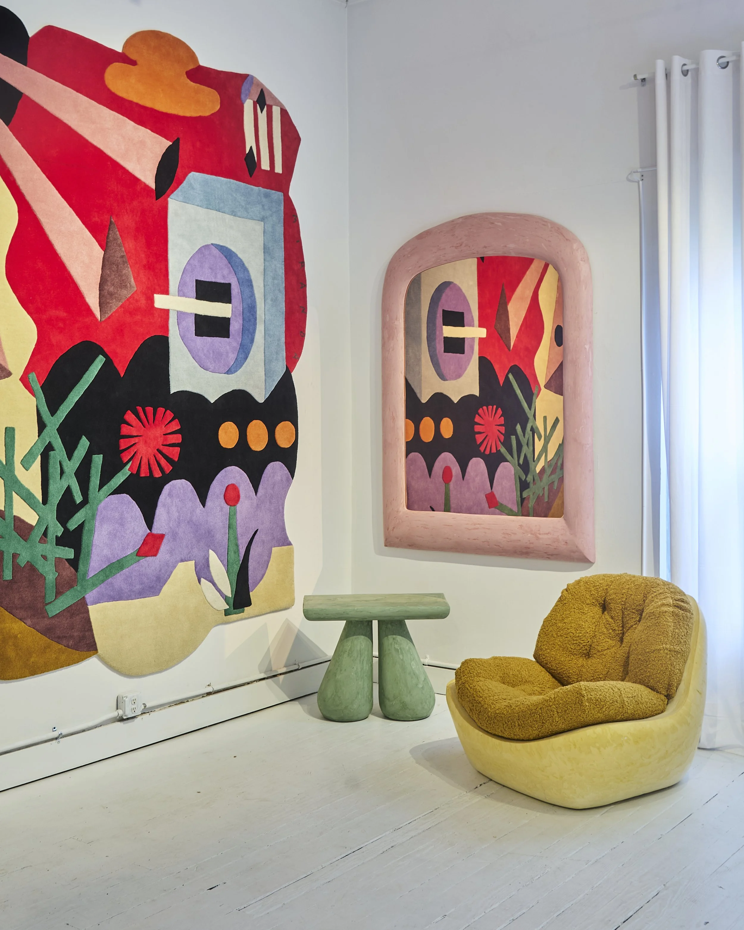 Interior of an art gallery with abstract colorful art on the wall, a green sculptural bench shaped like a mushroom, and a plush yellow lounge chair.