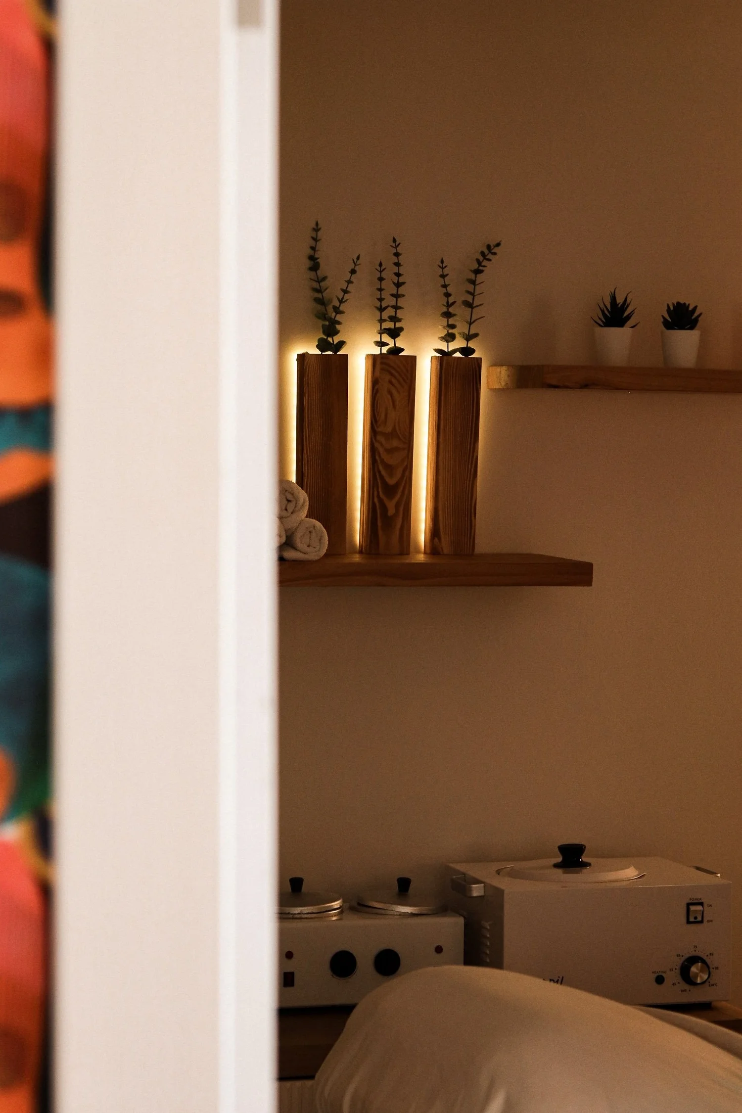 Glowing shelf with wood vases beside wax warmers