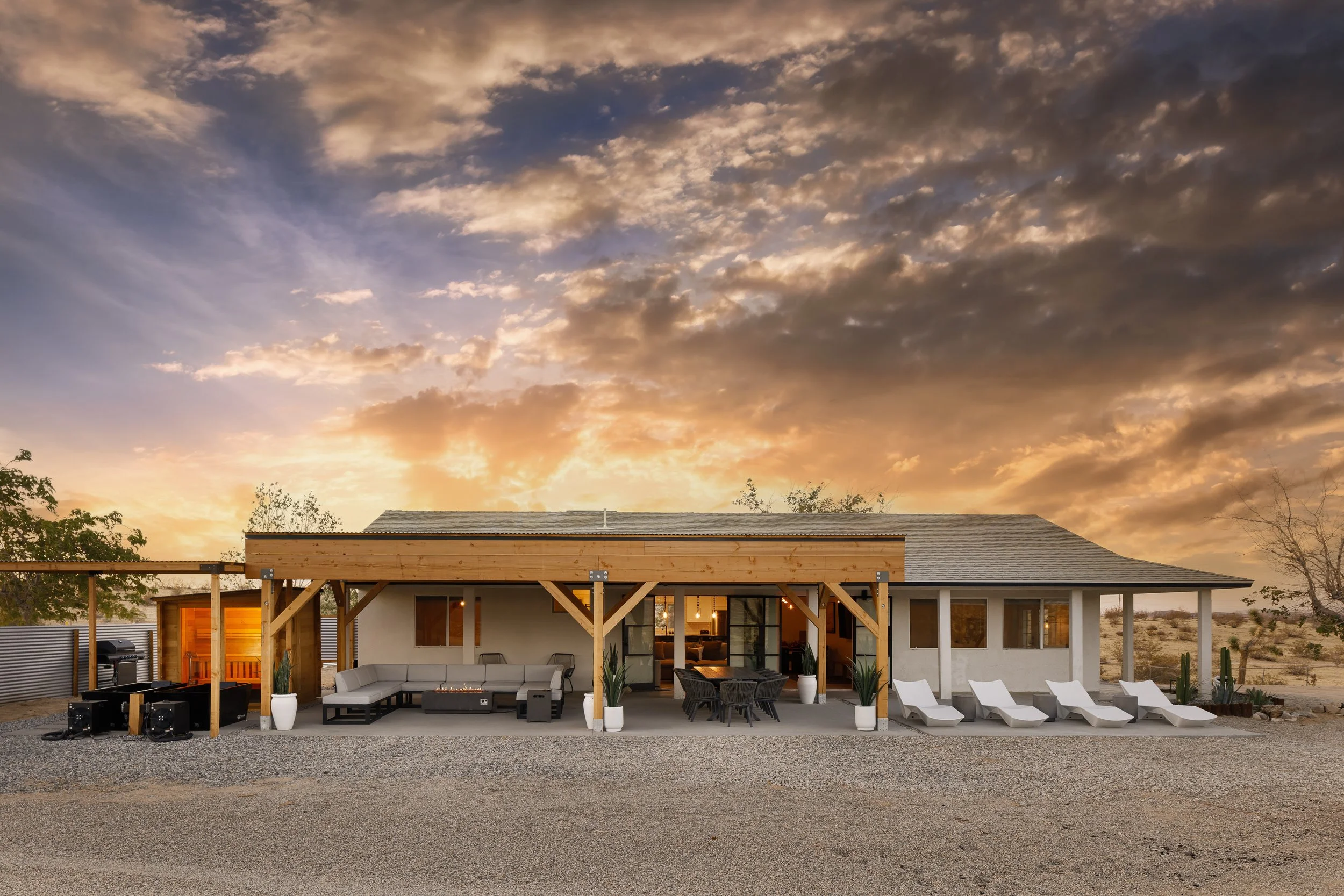 Modern house with outdoor patio and lounge chairs, sunset sky with clouds