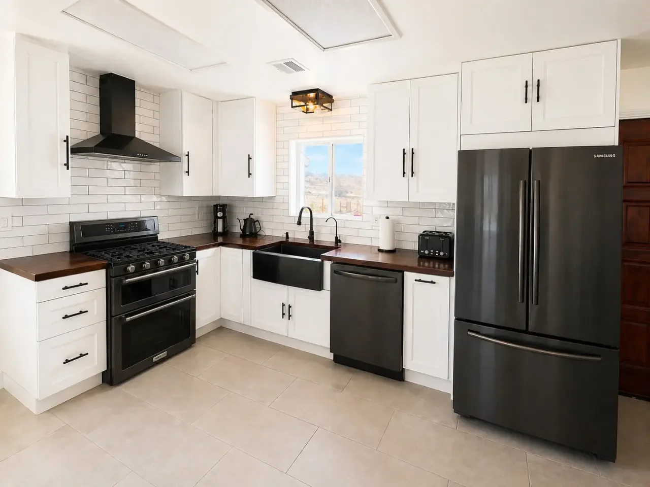 Modern kitchen with white cabinets, black appliances, and a brick backsplash. Included are a refrigerator, oven, sink, and small countertop appliances.