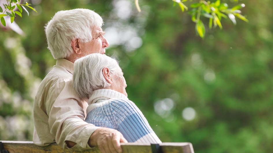Two elderly women sitting on a park bench enjoying nature.