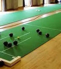 Indoor bocce ball court with black and green balls placed on green surface