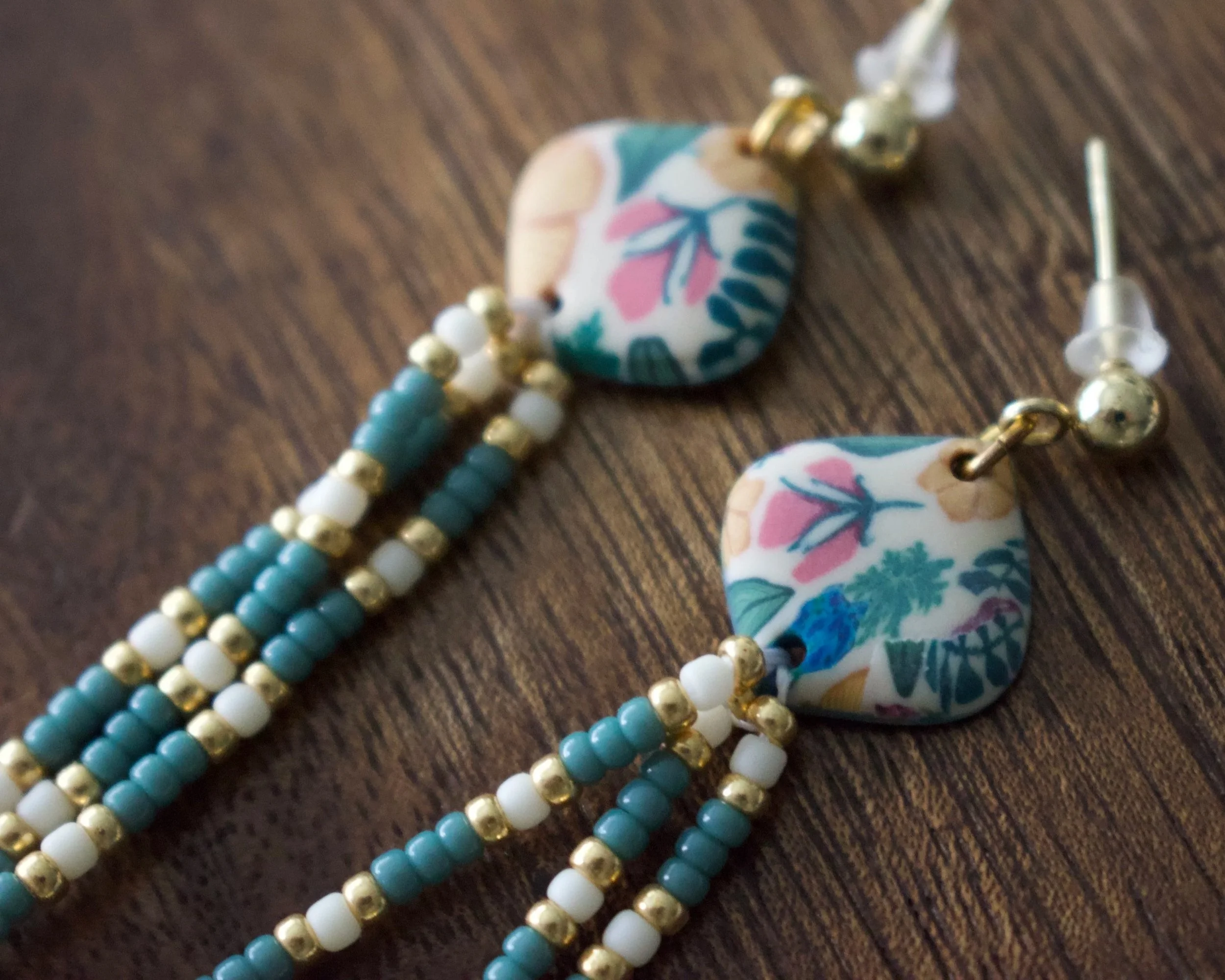 Colored beads, a floral pendant, and a piece of jewelry on a wooden surface.