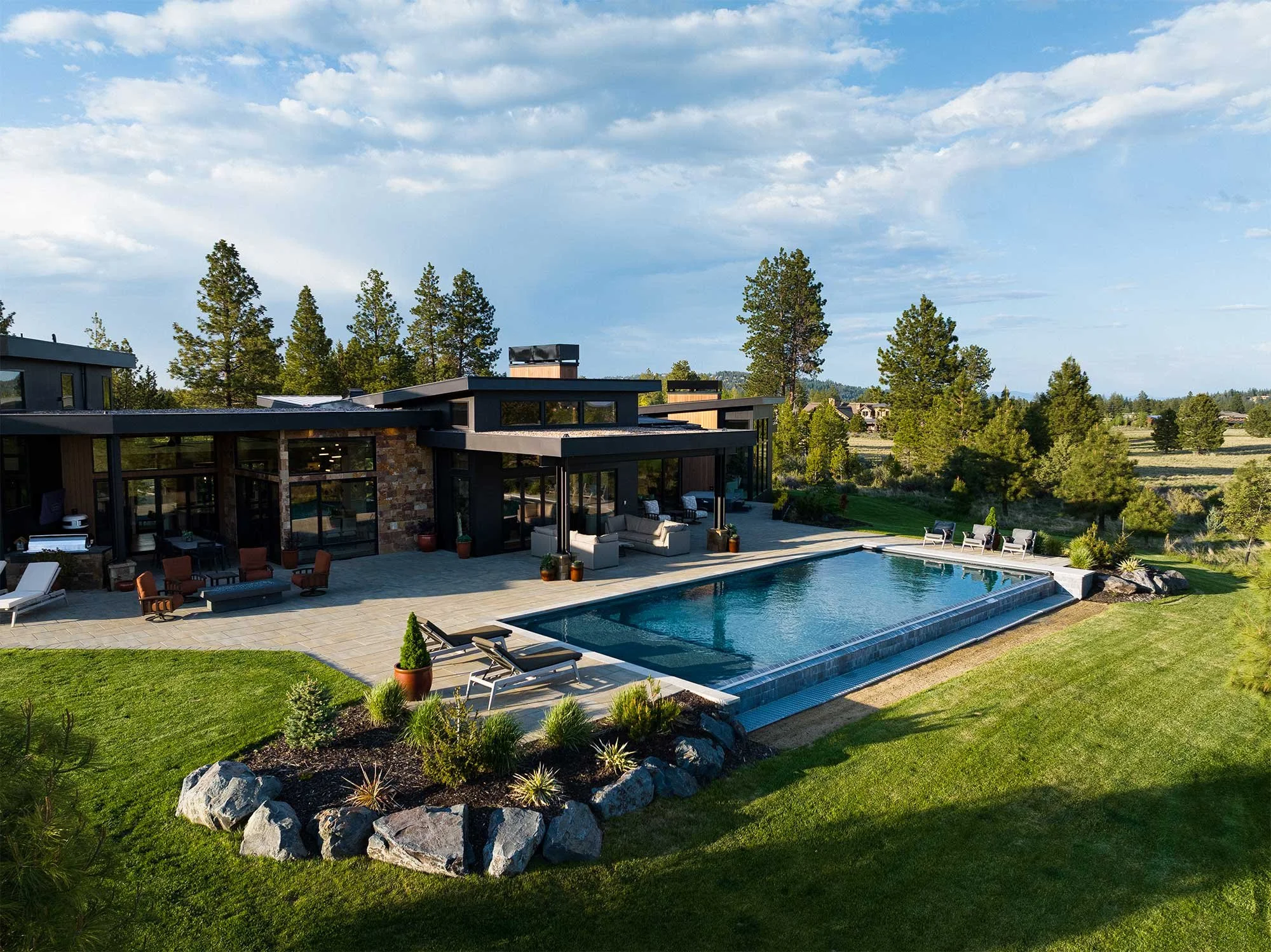 Rear exterior of a contemporary custom home with a swimming pool, patio and landscaped yard in Bend, Oregon.