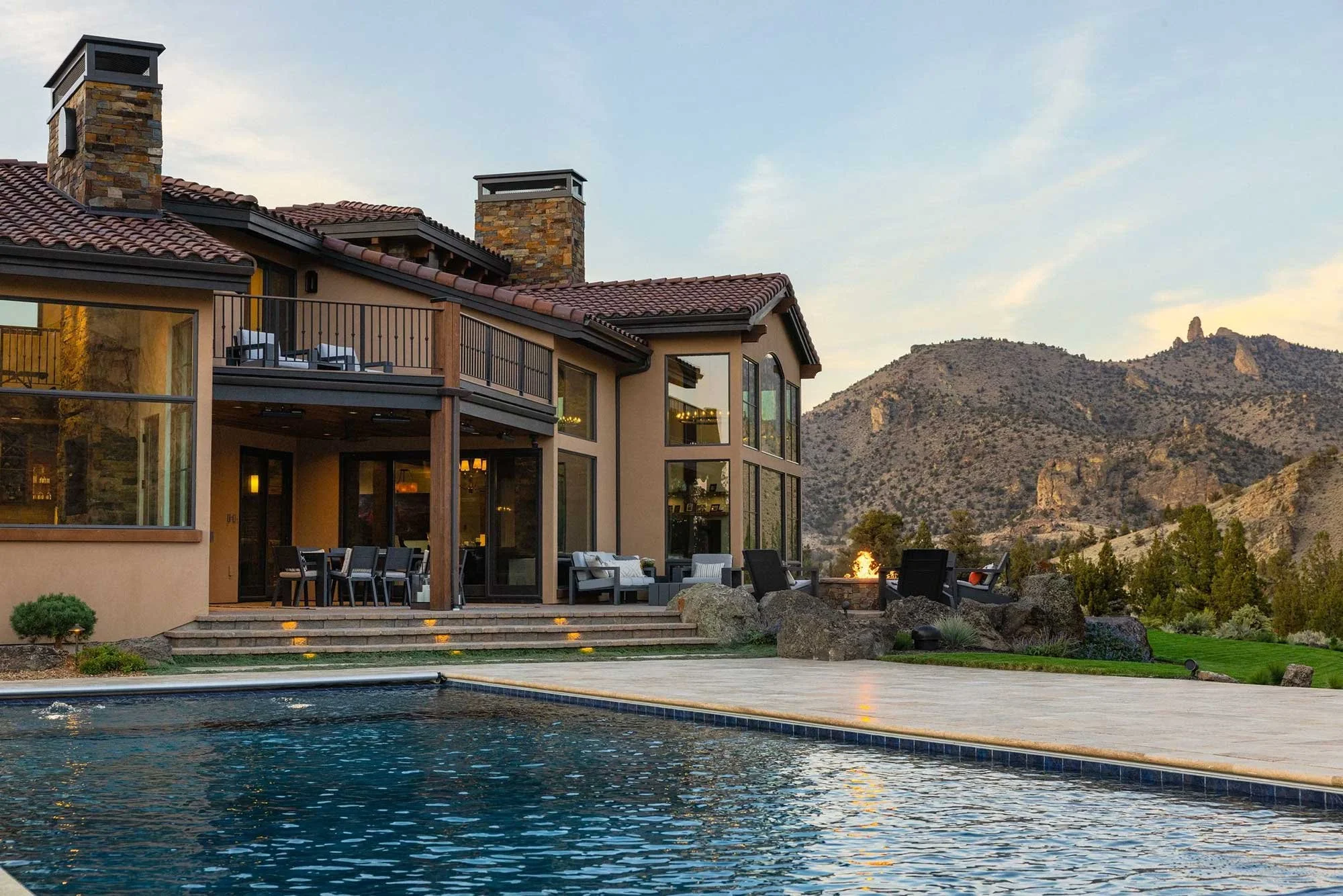 The exterior of a luxury home with a pool and few of the mountains.
