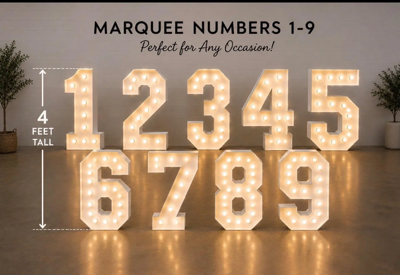 Large illuminated marquee numbers 1 through 9 arranged on a wooden floor with potted plants on each side, labeled as 4 feet tall, with text 'Marquee Numbers 1-9 Perfect for Any Occasion!' at the top.