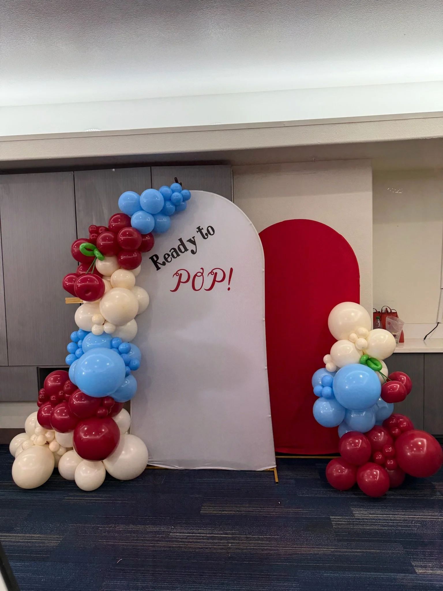 Balloon arch with red, white, and blue balloons and a sign reading "Ready to POP!"