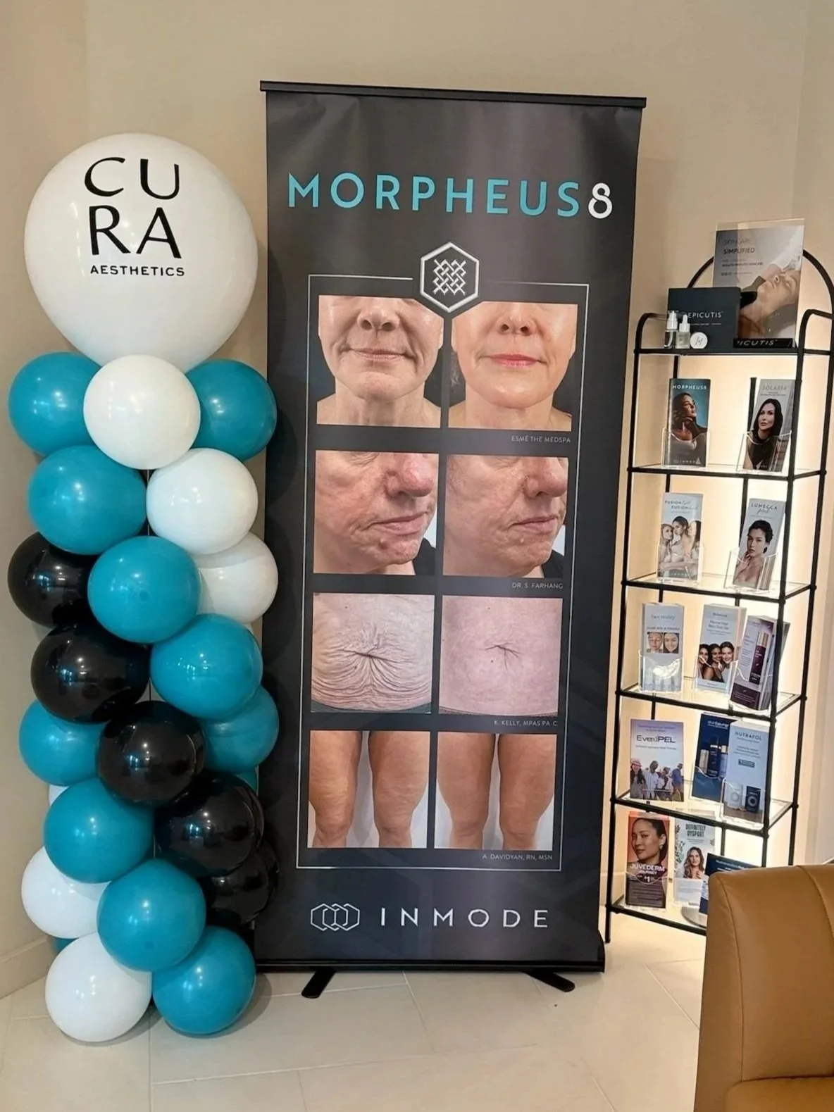 A promotional display for a cosmetic or dermatology treatment showing before-and-after photos of aging skin improvements, with a balloon column on the left and a brochure stand on the right.