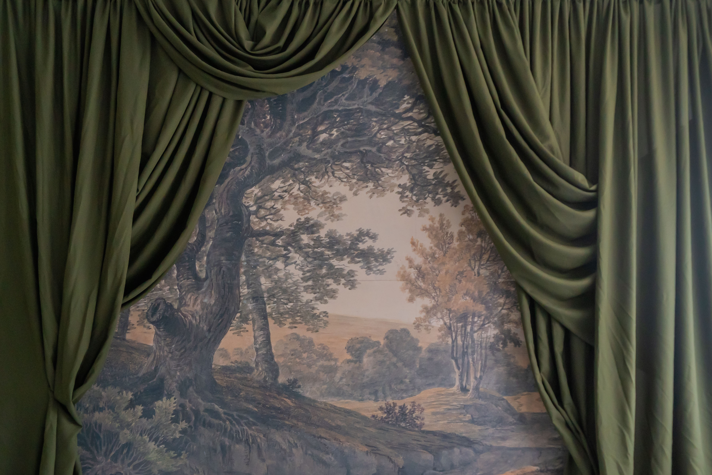 Painting of a large tree with twisting branches, viewed through green curtains.