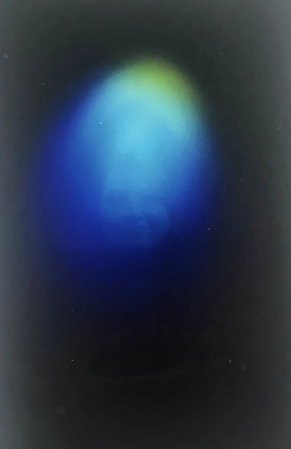 A blurry image displaying a blue-green light on a dark background.