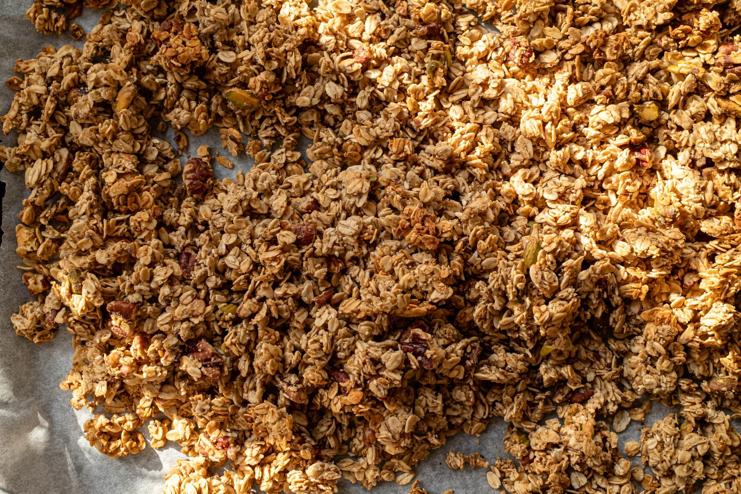 Close-up of homemade granola bars on parchment paper, showing oats, nuts, and dried fruit.